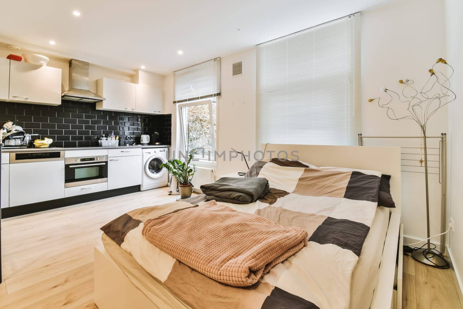 a bedroom with a bed, microwave and oven in the corner next to each other room's kitchen area