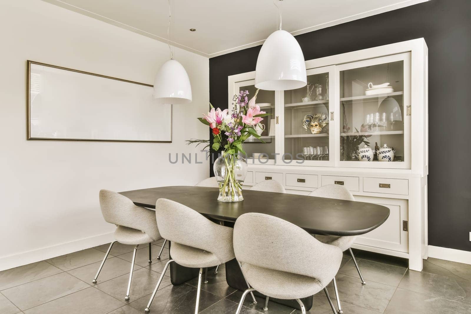 a black and white dining room with flowers in a vase on the table next to two chairs that are facing towardss