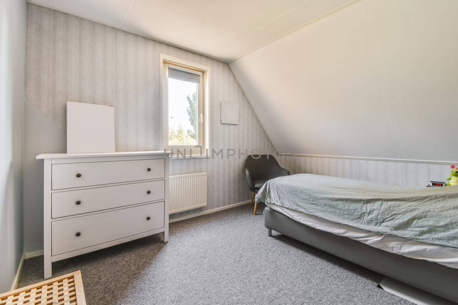 a bedroom with a bed, dresser and window in the attic house stock photo - 1237896
