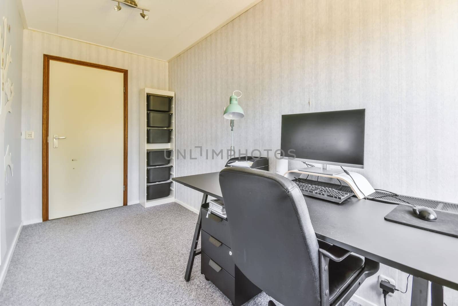 an office space with a computer, monitor and keyboard on the desk in front of the door to the room