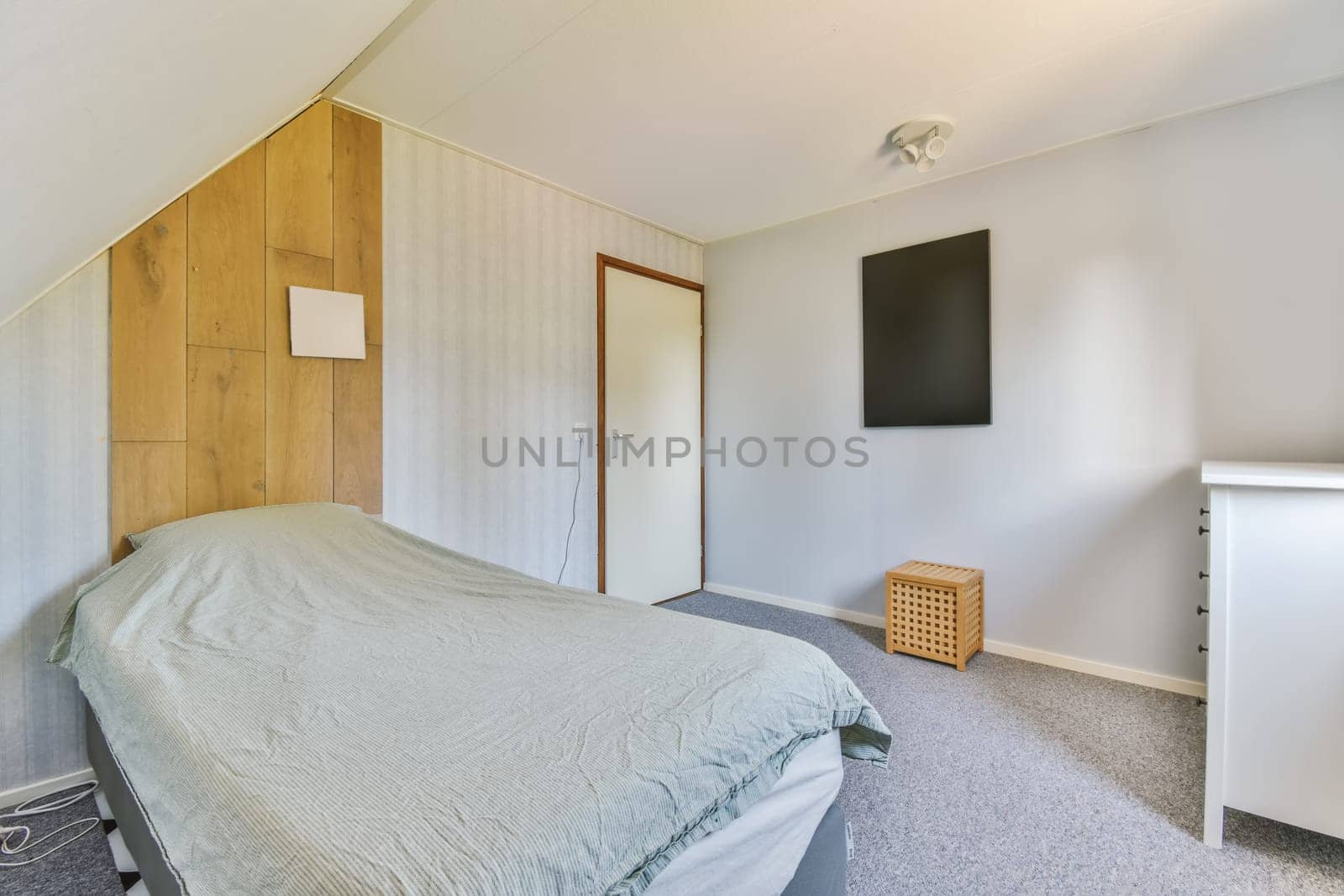 a bedroom with a tv on the wall and a bed in the fore - image is taken from an angle