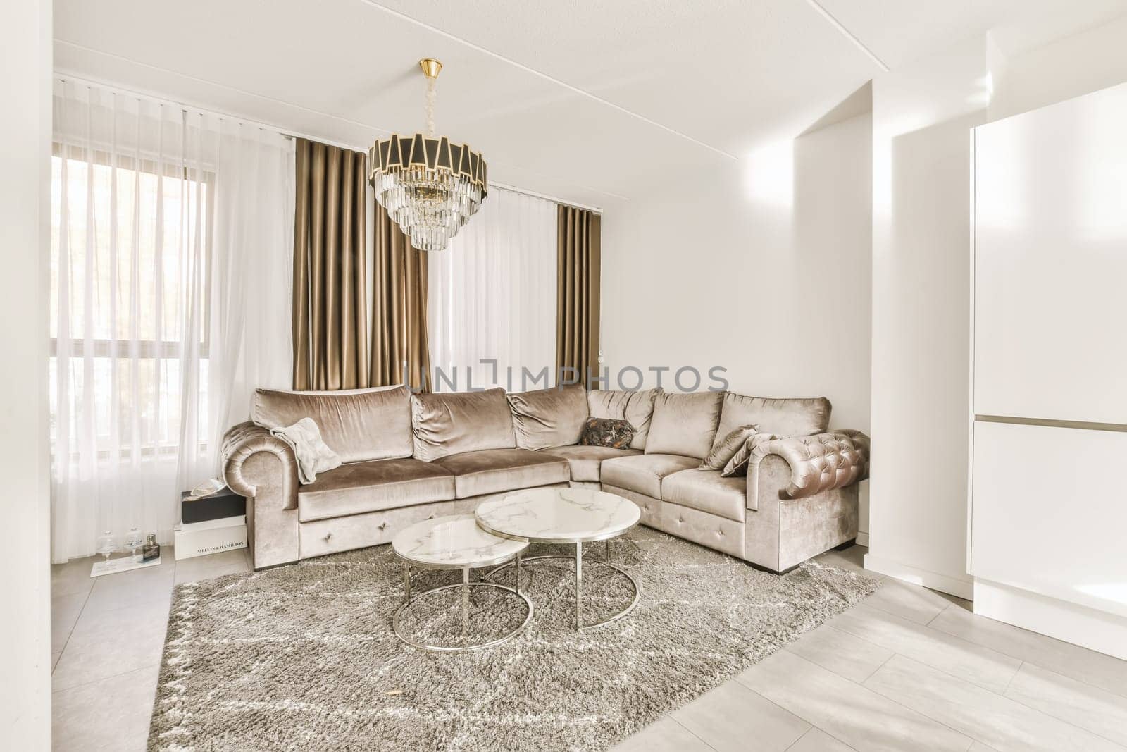 a living room with couch, coffee table and chandels on the wall in the room is very white