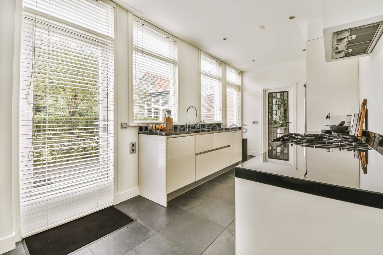 a modern kitchen with black counter tops and white shutters on the windows in the photo is taken from outside