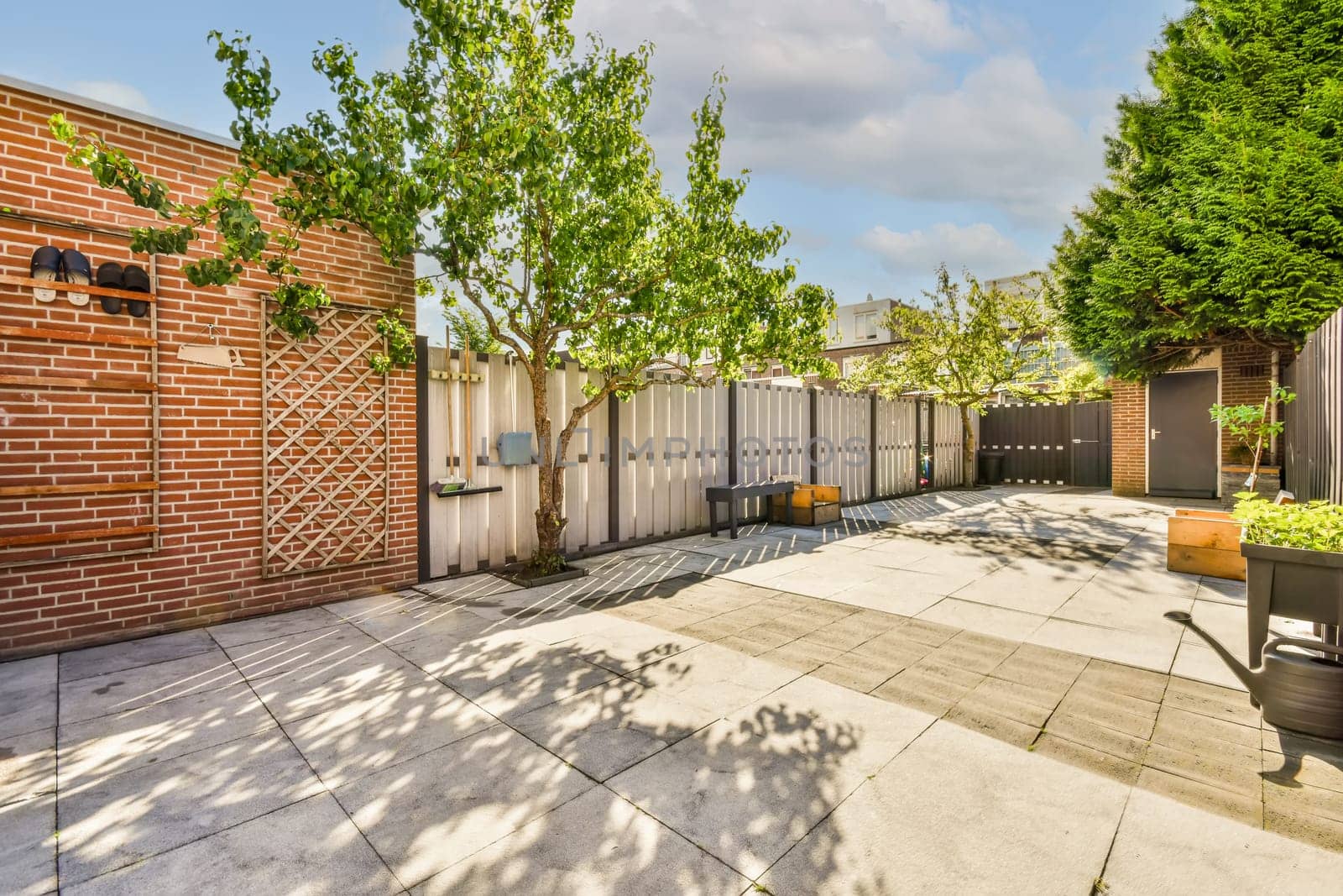 a backyard area with brick walls, trees and potted planters in the fore - image is taken from above