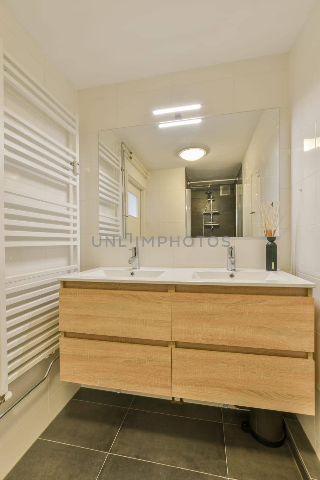 a modern bathroom with wood cabinets and white tiles on the floor, along with a large mirror over the sink