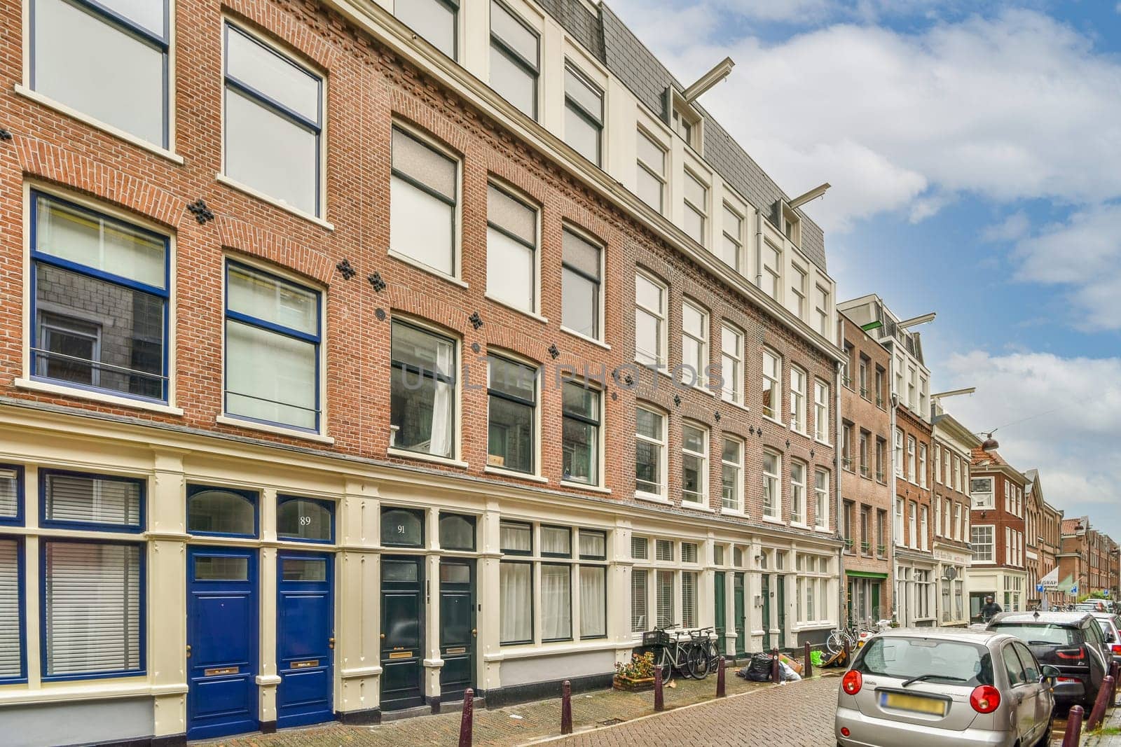 a city street with cars parked on the side and people walking down the street in front of buildings, all facing to one another