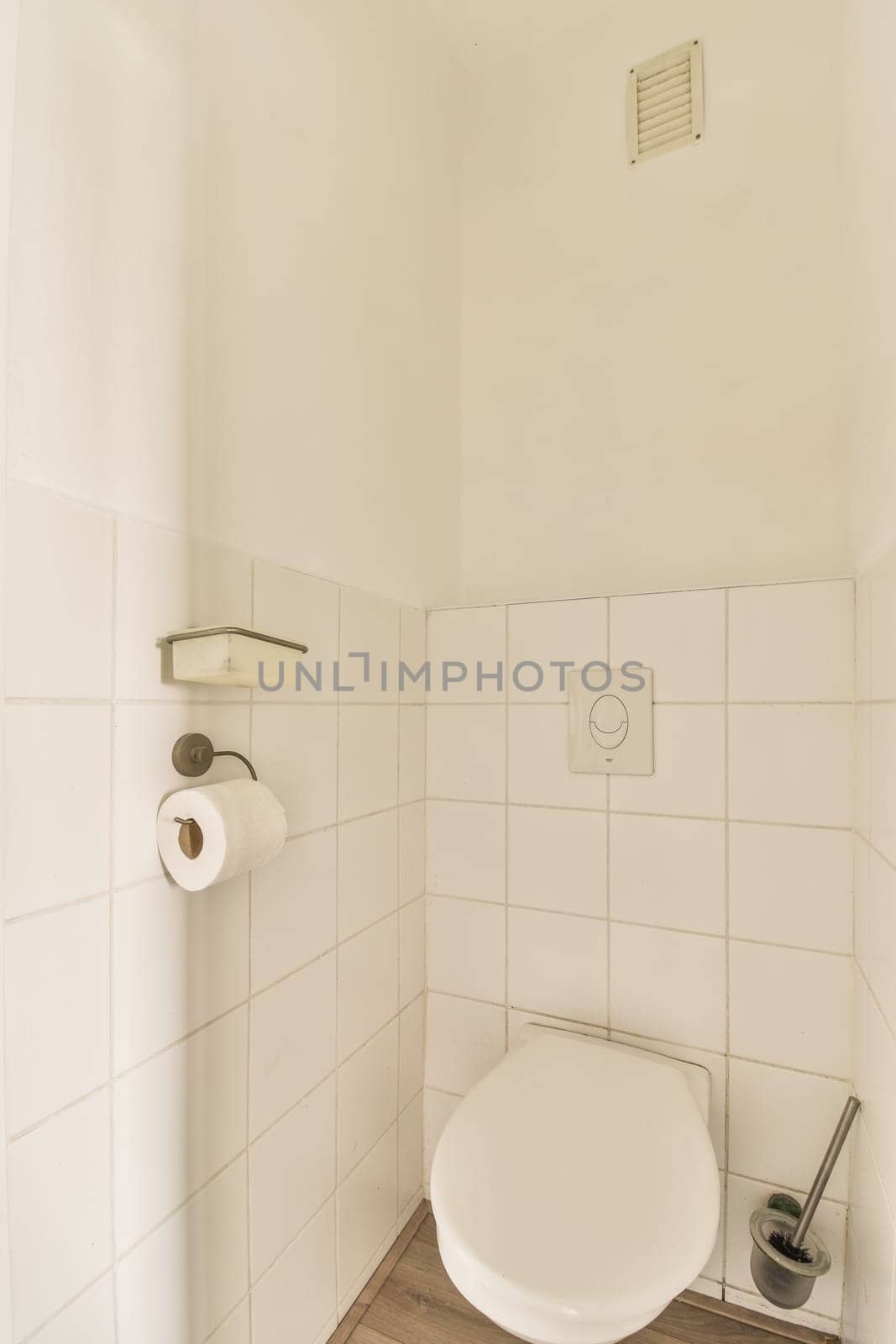 a white toilet in a small bathroom with wood flooring and tile on the walls there is a trash can be seen