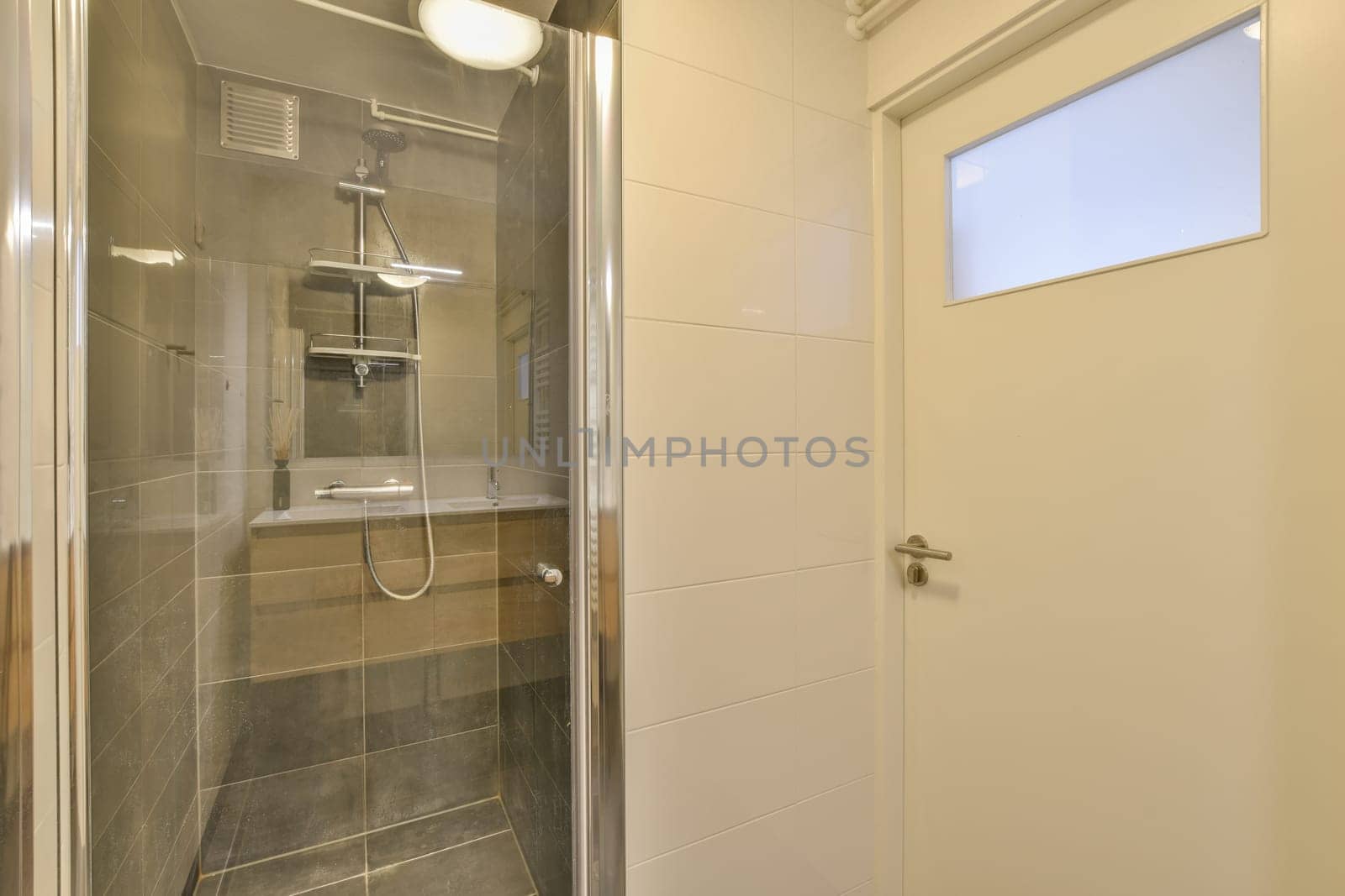 a bathroom with a glass shower door and white tiles on the wall behind it is a toilet in front of a window