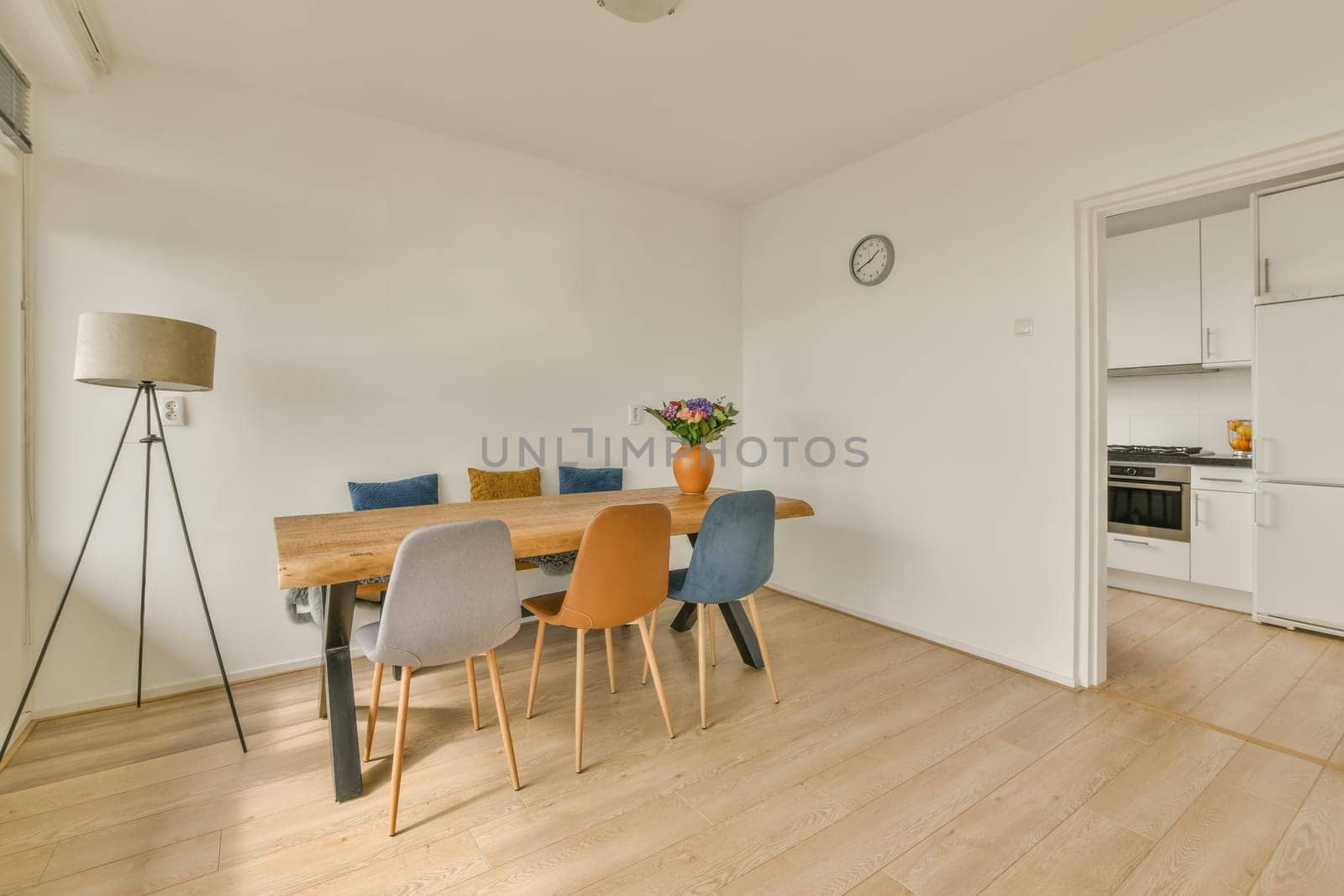 a dining table and chairs in a room with white walls, hardwood flooring and light colored furniture on the right side