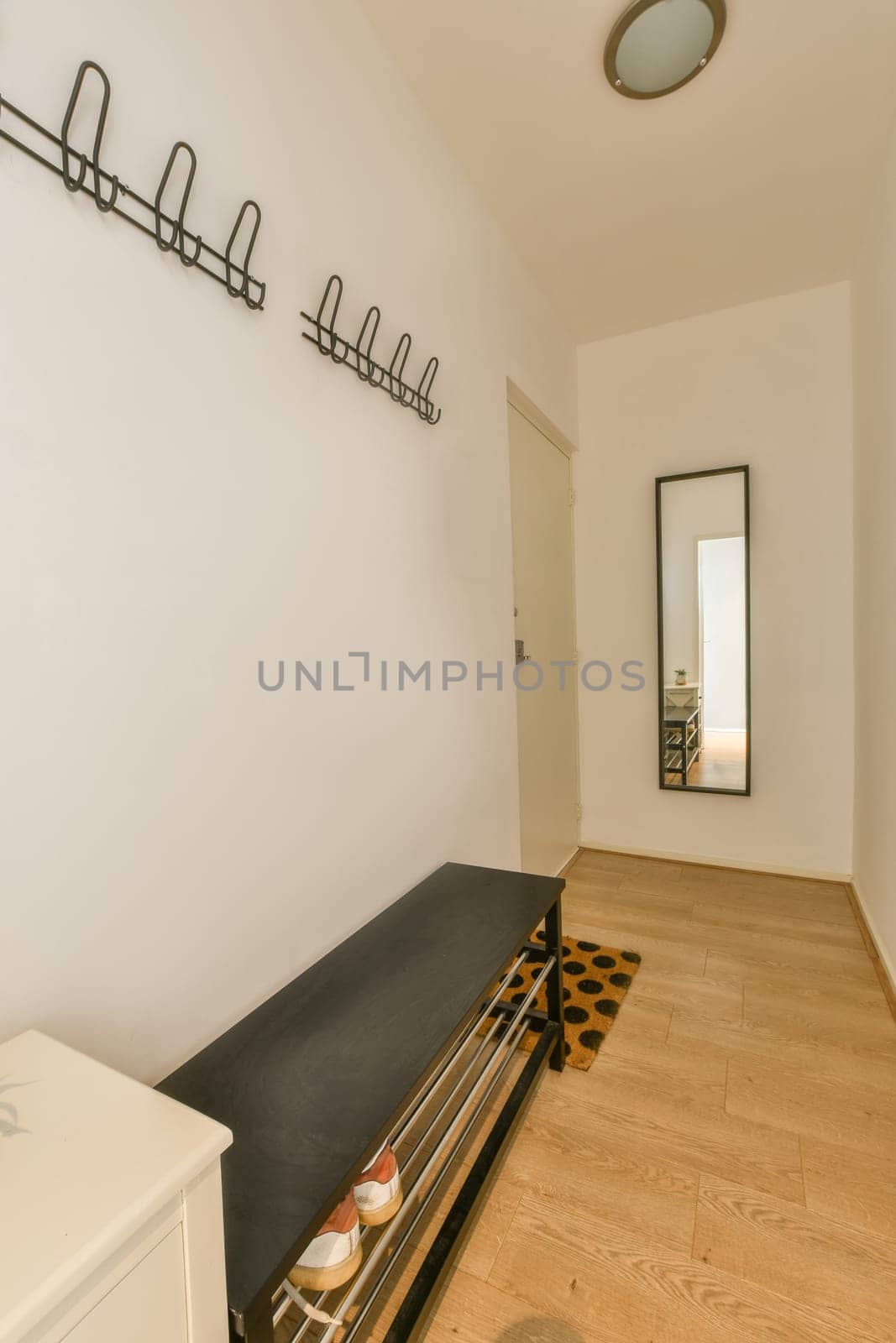 a living room with white walls and wood flooring on the wall, there is a mirror hanging above it