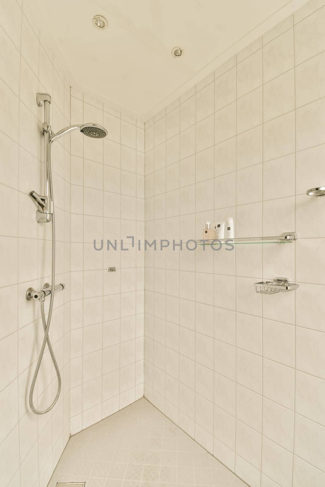 a white tiled bathroom with shower head and hand rails in the wall is made out of ceramic tiles on the floor