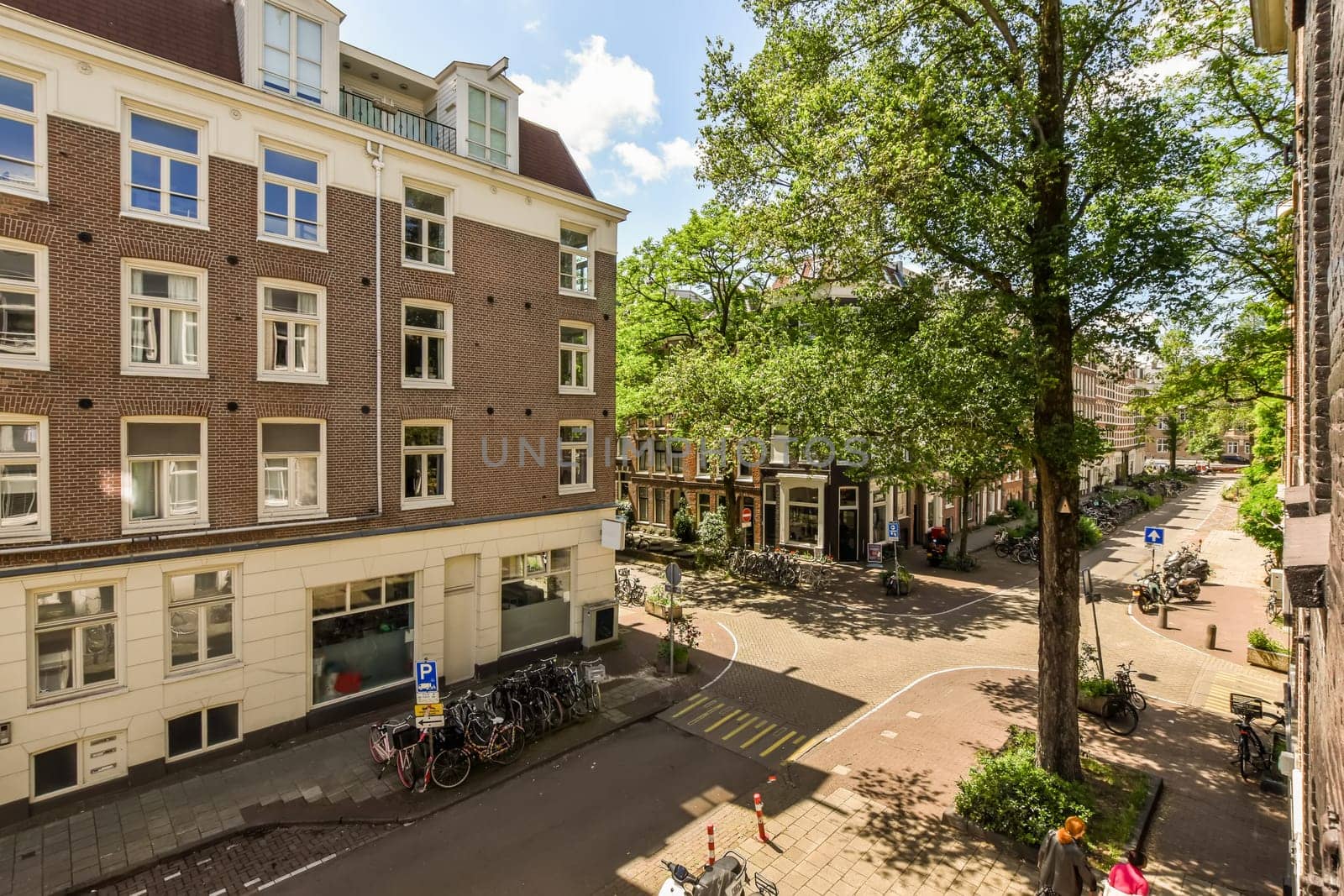 a city street with buildings and bicycles parked on the sidewalk in front of an apartment building, taken from above