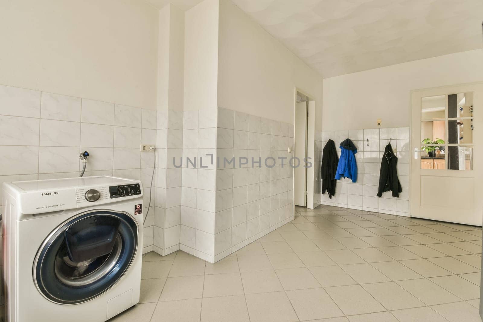 a laundry room with a washer, dryer and clothes hanging on the wall next to the washing machine