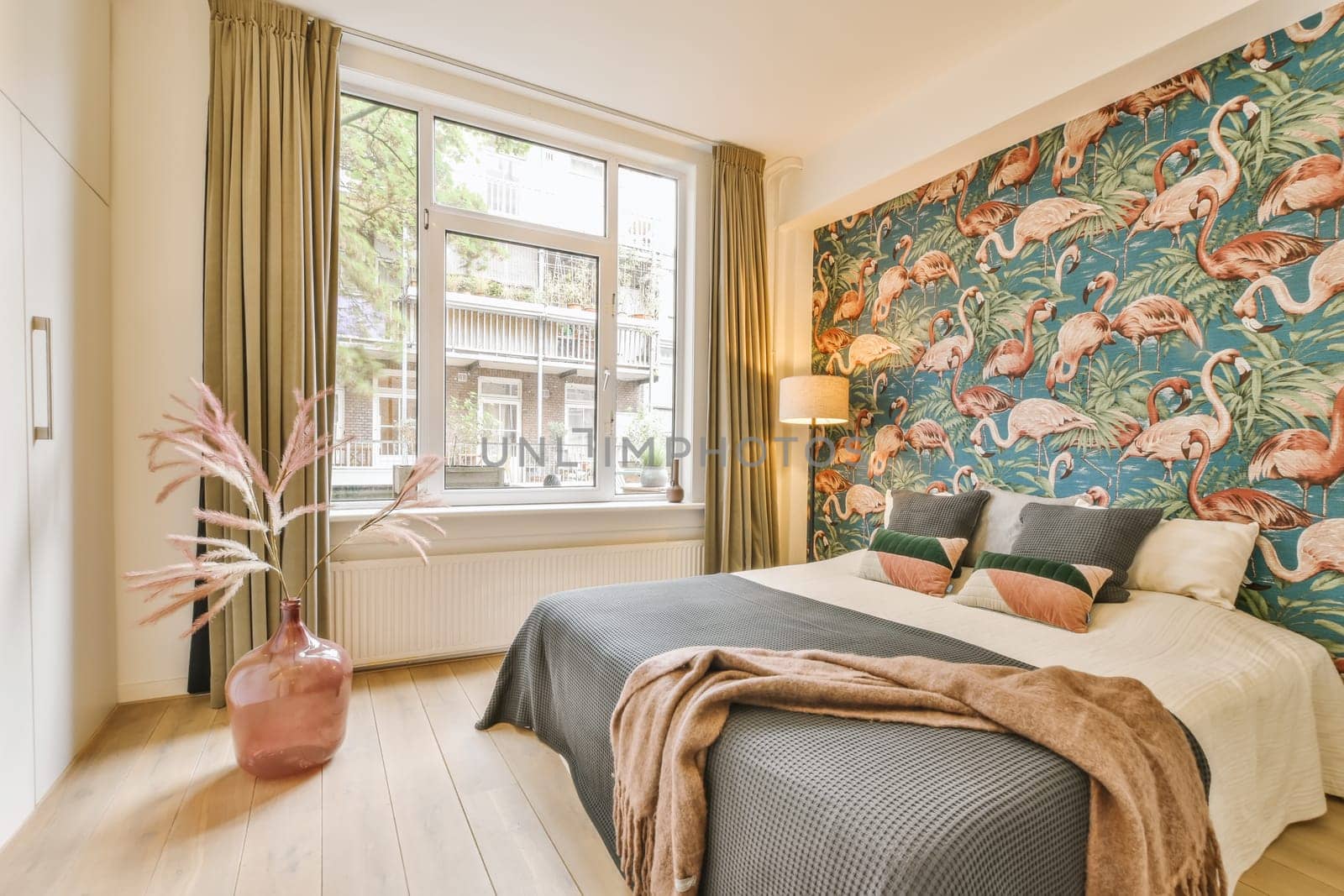 a bedroom with flamings on the wallpaper and wooden floors in front of the bed, there is a pink plant next to