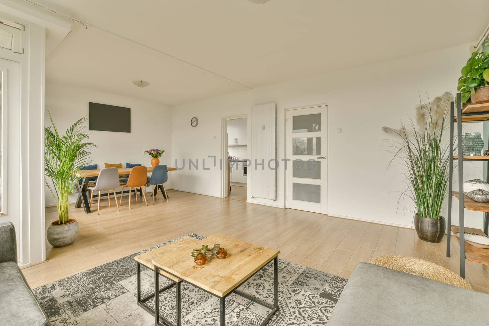 a living room with white walls and wood flooring, there is a tv on the wall in the corner