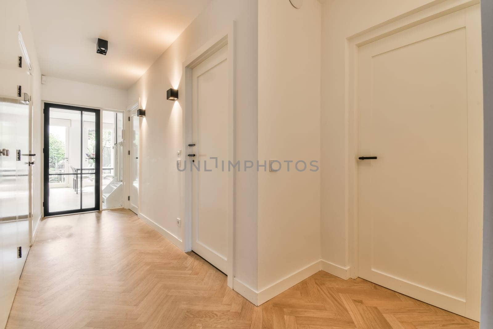an empty room with wood flooring and white walls on either side, there is a black door in the corner