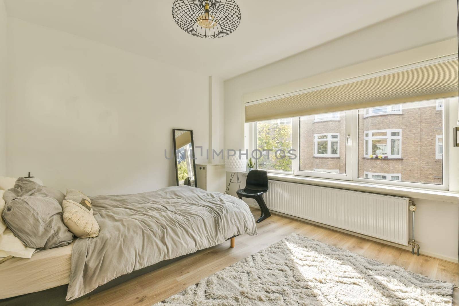 a bedroom with white walls and wood flooring in the middle of the room, there is a large window that looks out into