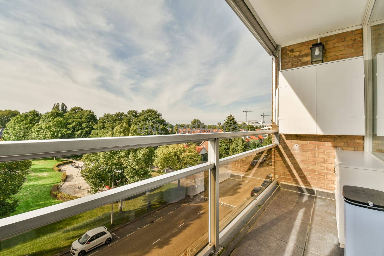 a balcony with a view of the trees and buildings in the distance, taken from an apartment window looking out onto the street