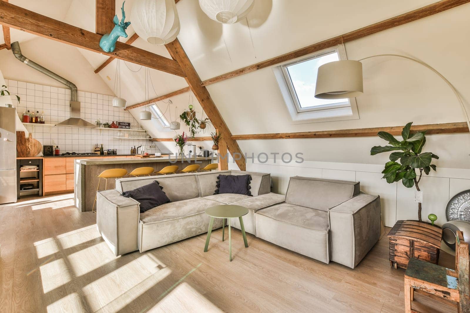 a kitchen and living room in an attic style home with white walls, hardwood flooring and exposed ceilings