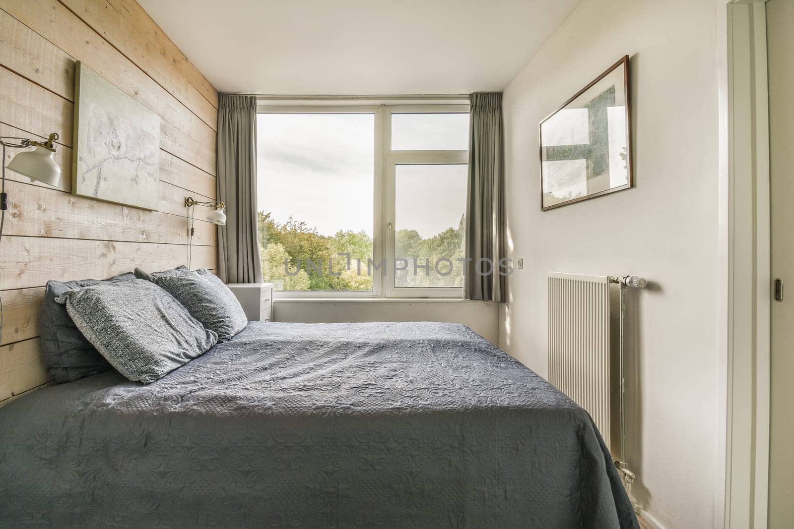a bed in a room with wood paneling on the wall and window overlooking out onto the street below it
