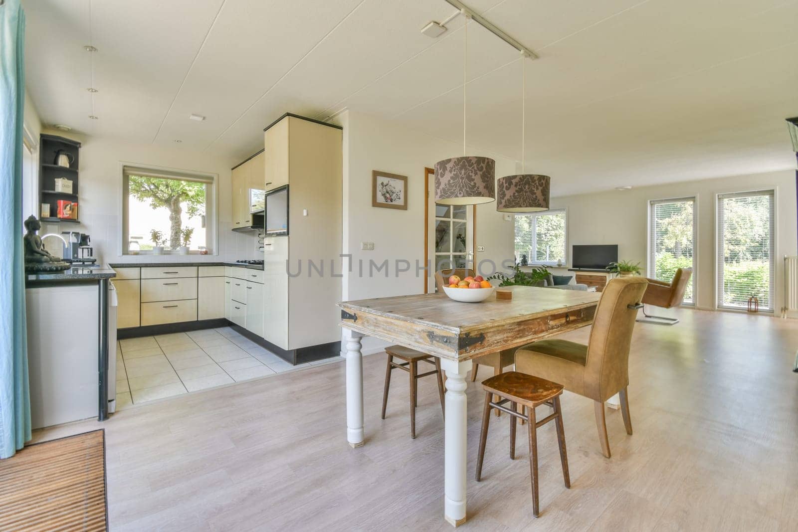 a kitchen and dining area in a house with wood flooring, white walls, wooden floors, and large windows