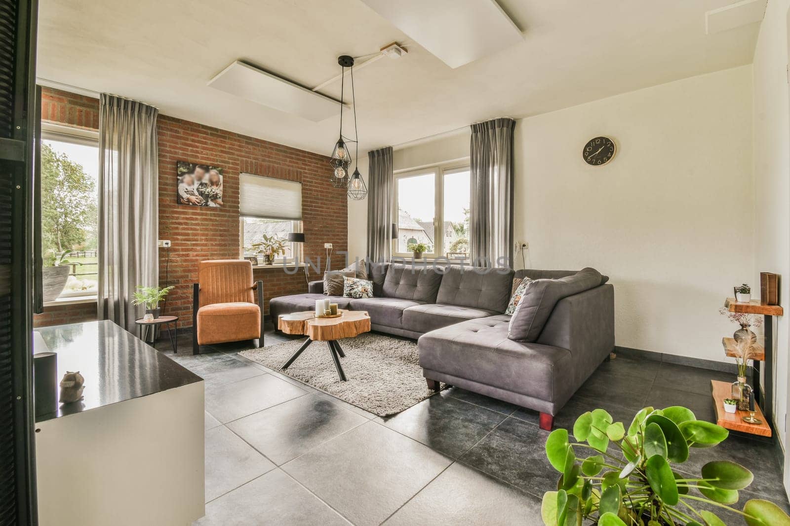 a living room with couches, chairs and plants in the center of the room there is a brick wall that has been painted
