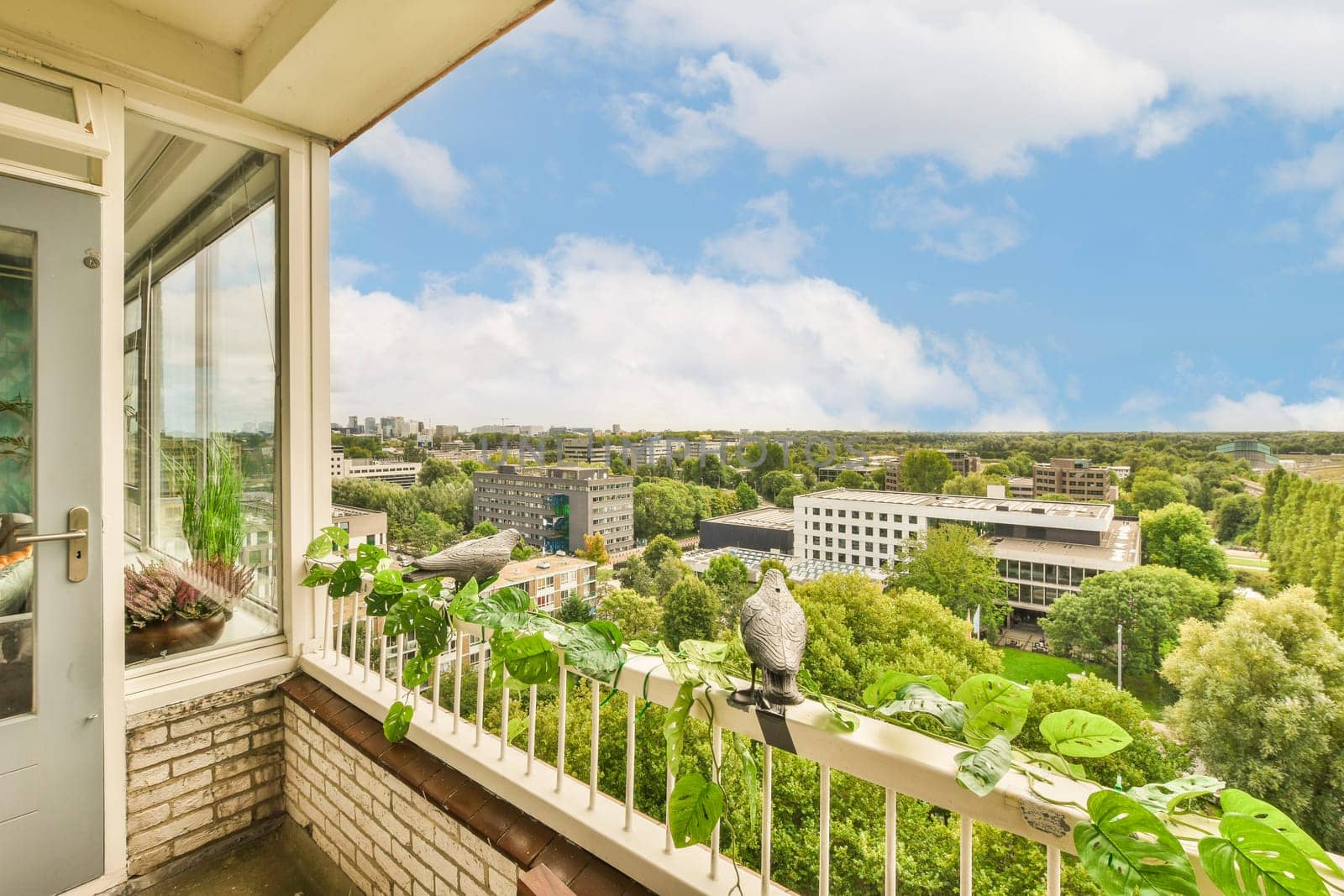a balcony with trees and buildings in the background, as seen from an apartment window looking out onto the street