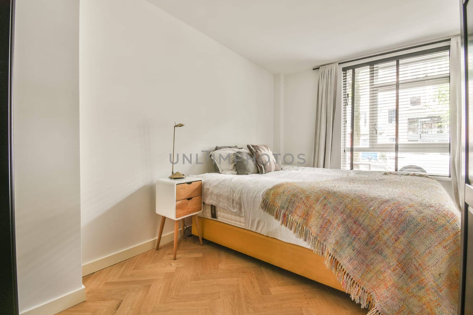 a bedroom with wood flooring and white walls, including a bed in the fore - image taken from above