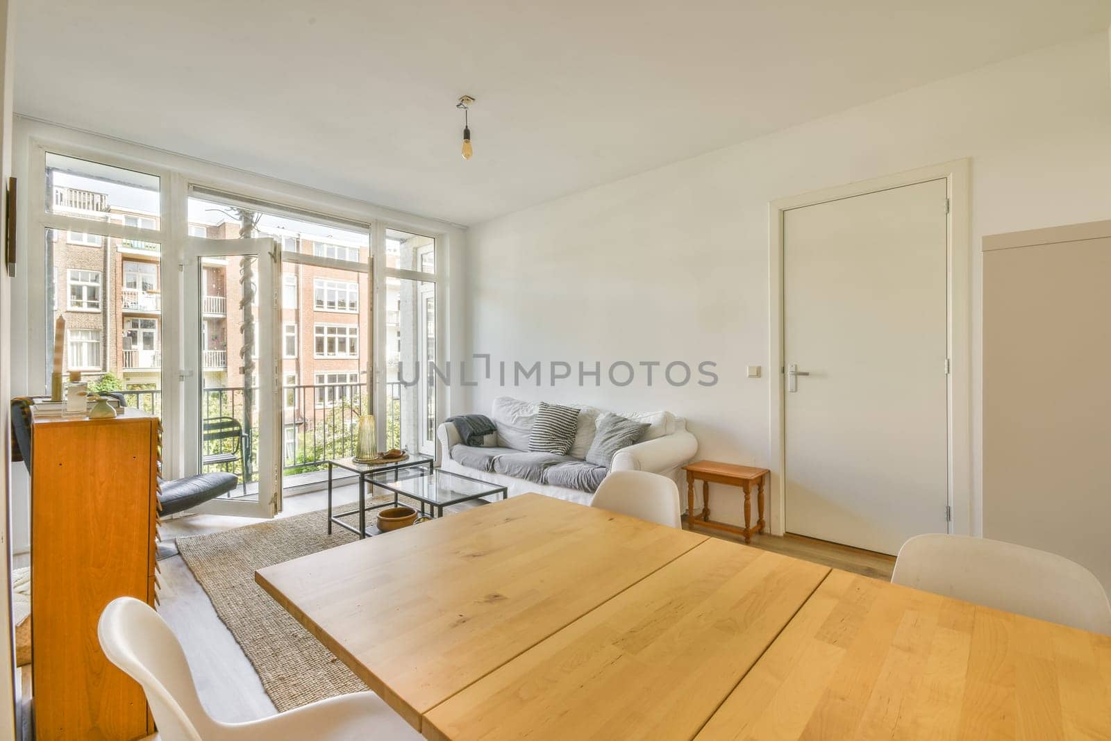 a dining table and chairs in a living room with sliding glass doors that open onto the balcony area to an outside patio
