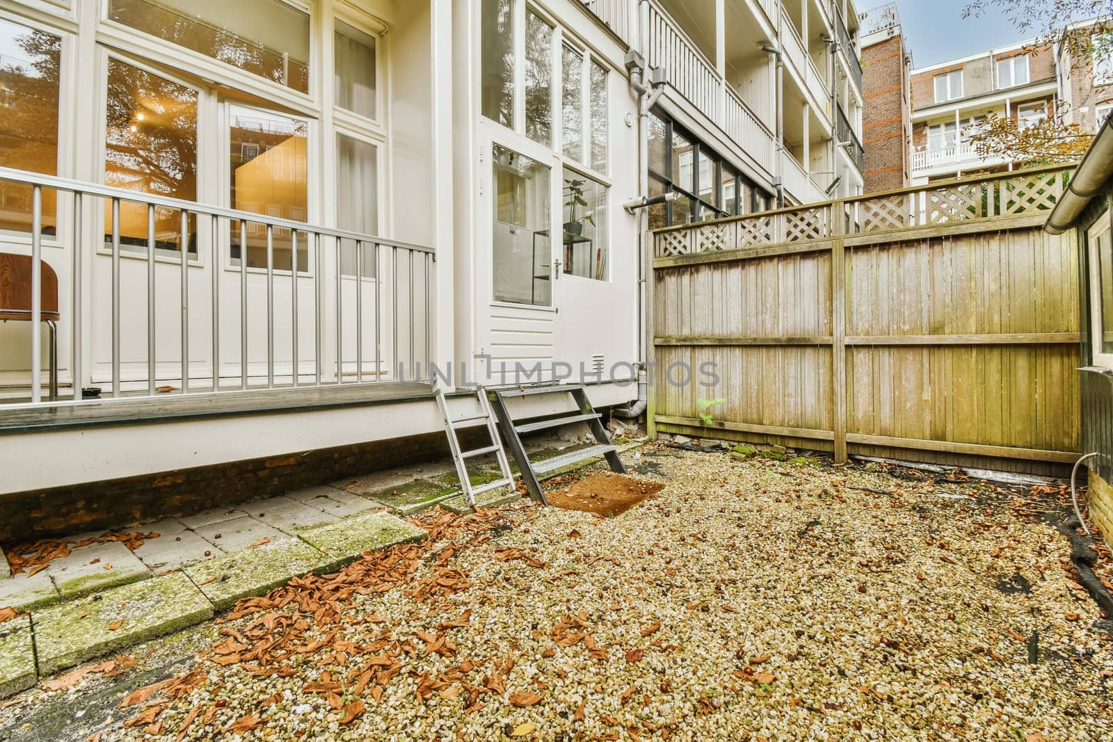a back yard with leaves on the ground next to a fence and some trees in the background is clear blue sky