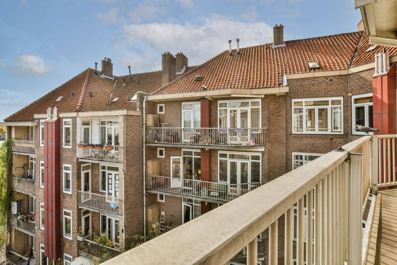 some houses in the city with red shutters and white balks on their windows, taken from an apartment balcony