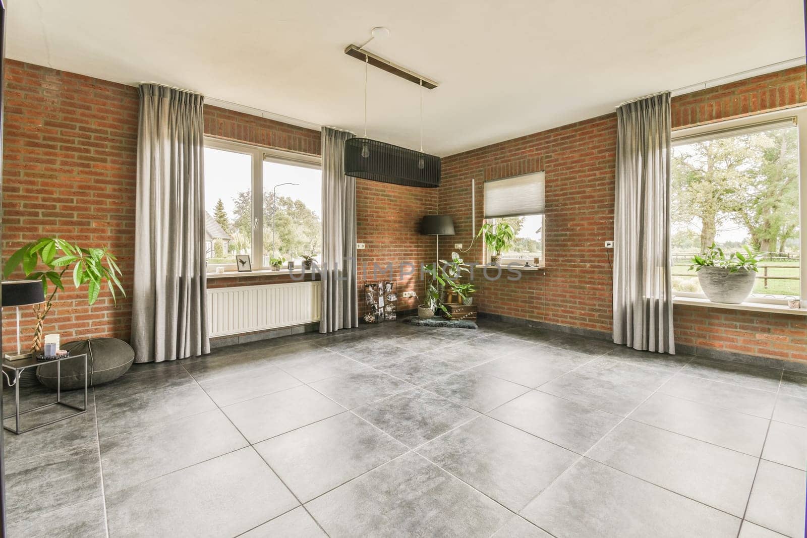 a living room with red brick walls and grey tiles on the floor, there is an open window to the outside