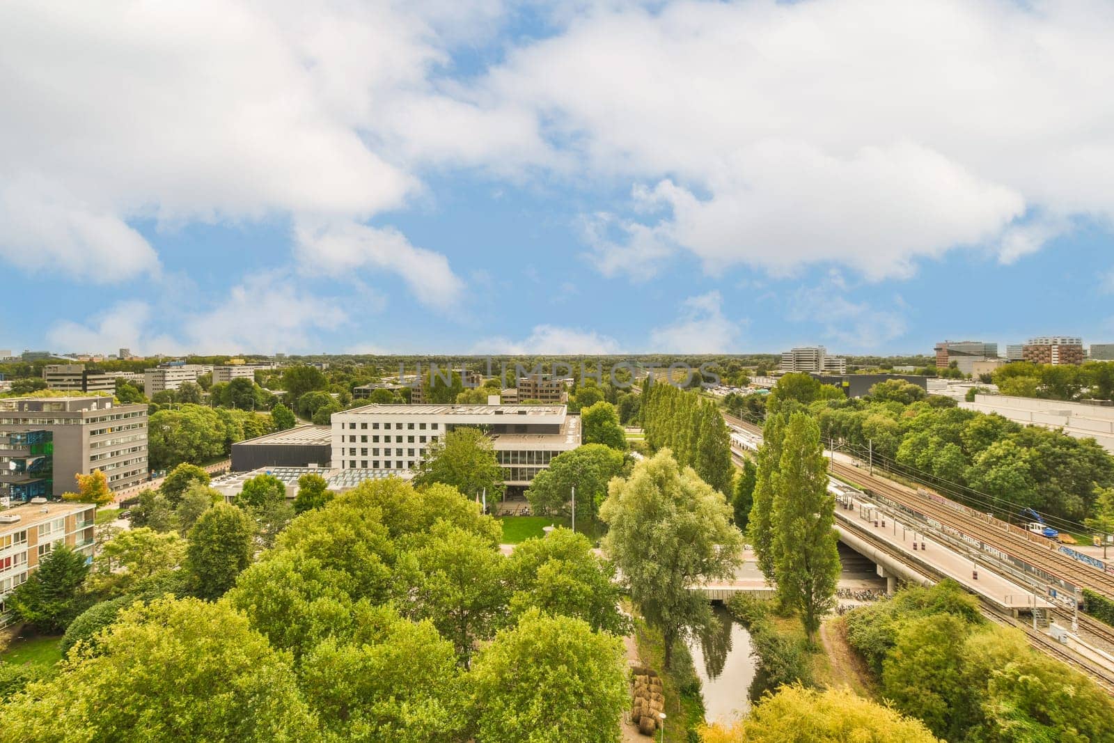 a city with trees and buildings in the fore - shot, taken from an aerial drone camera on a sunny day