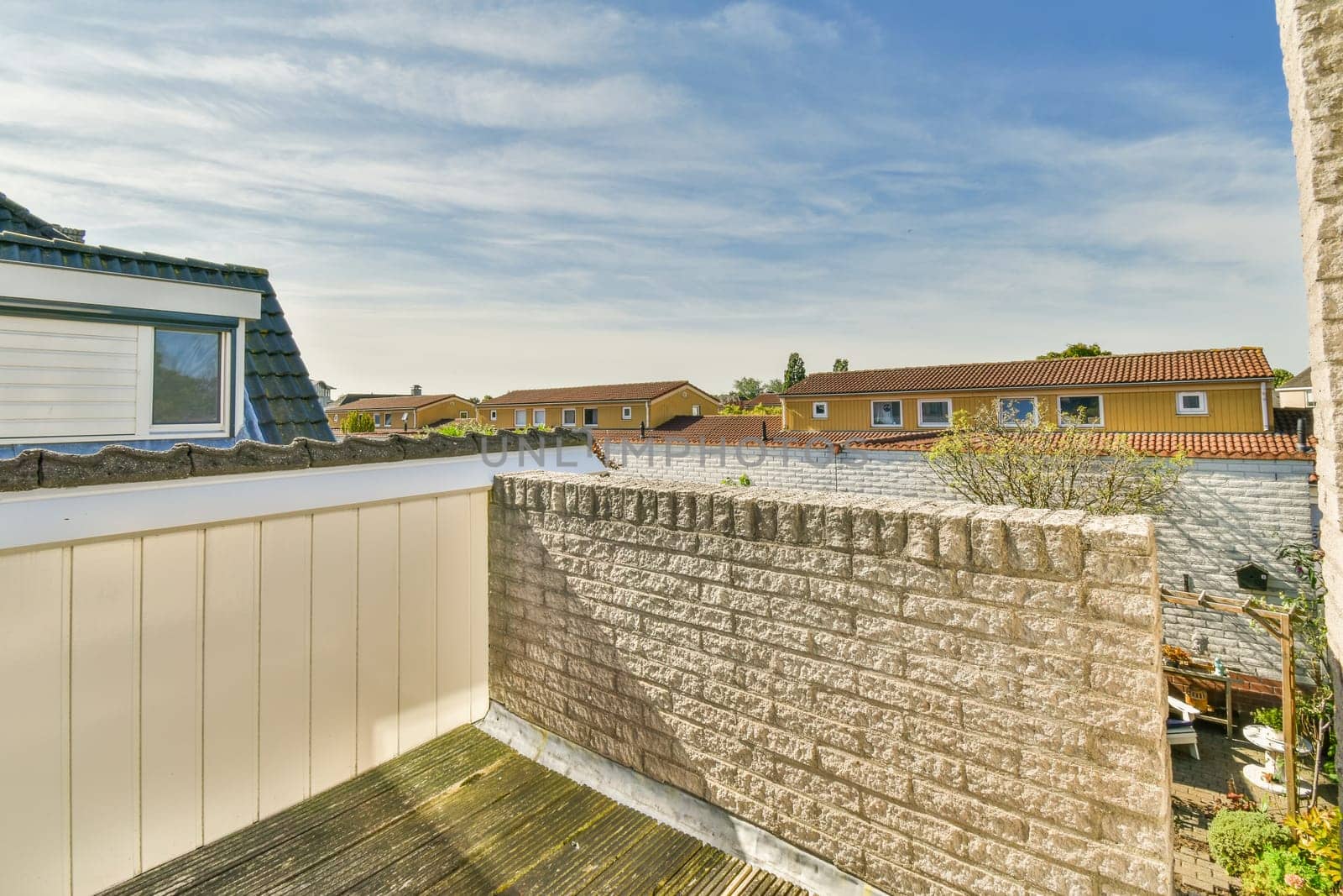 an outside area with some houses in the background and a blue sky above it, as seen from a window