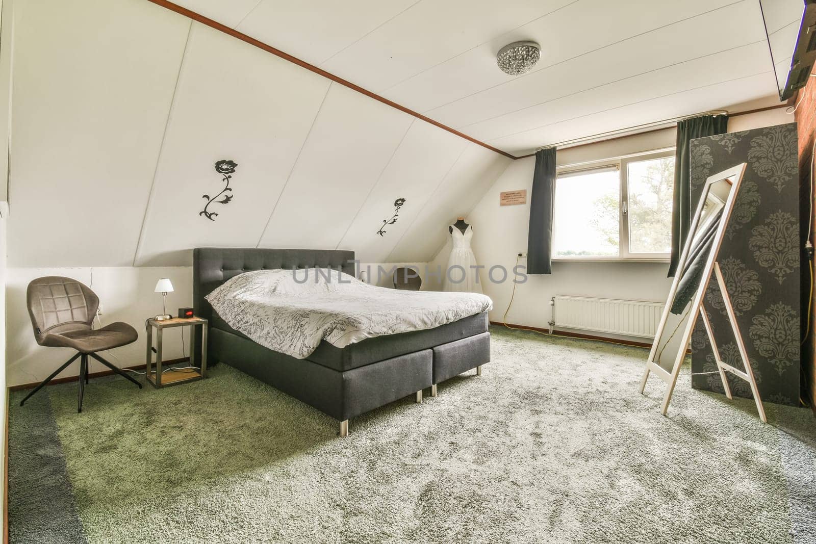 a bedroom with a bed, chair and tv on the wall in it's corner next to a window