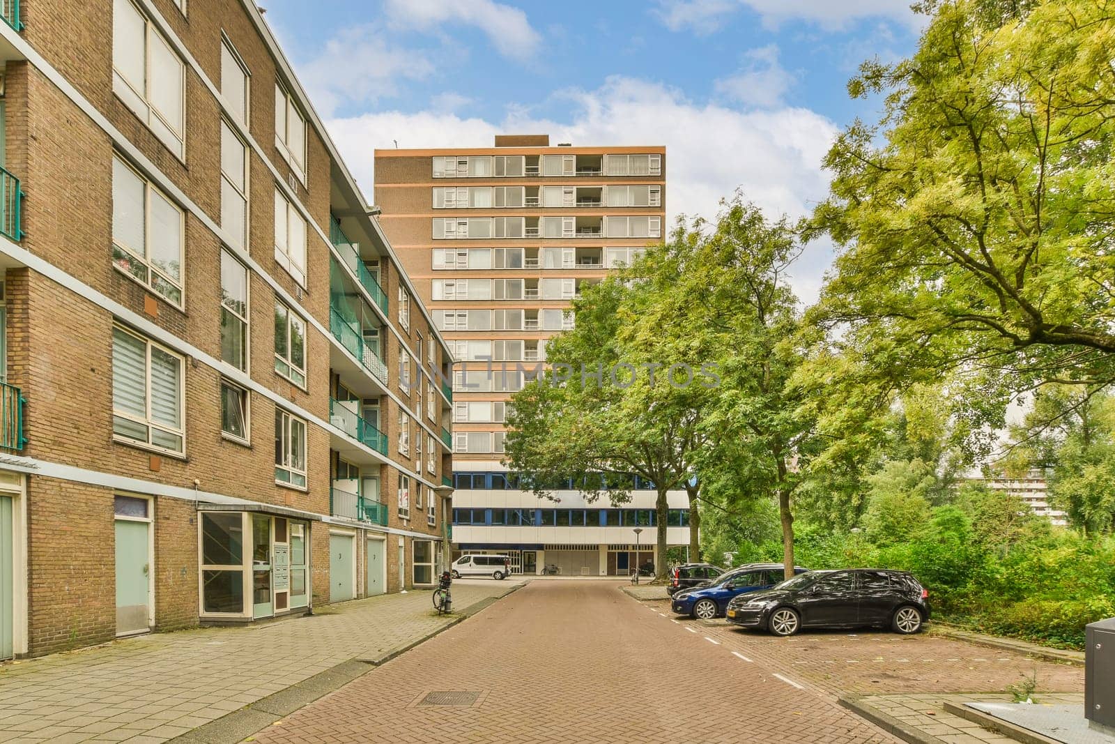 a city street with cars parked on the side and buildings in the back ground, some green trees are visible