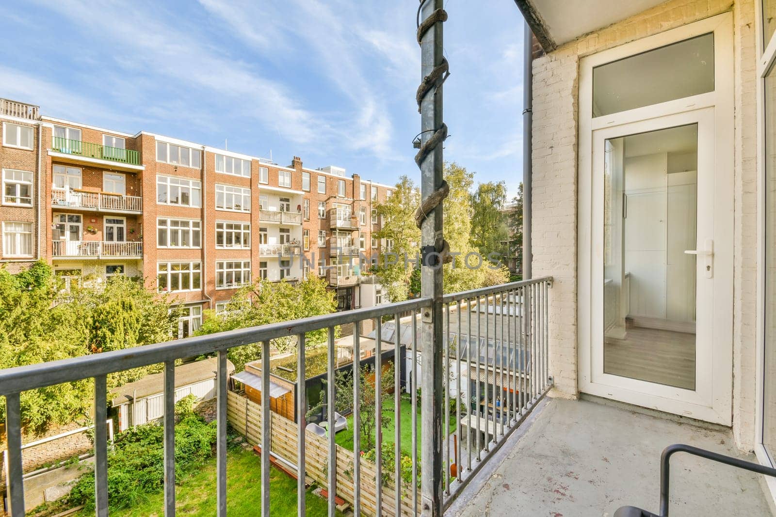 a balcony with trees and buildings in the background, taken from an apartment window looking out to the street below