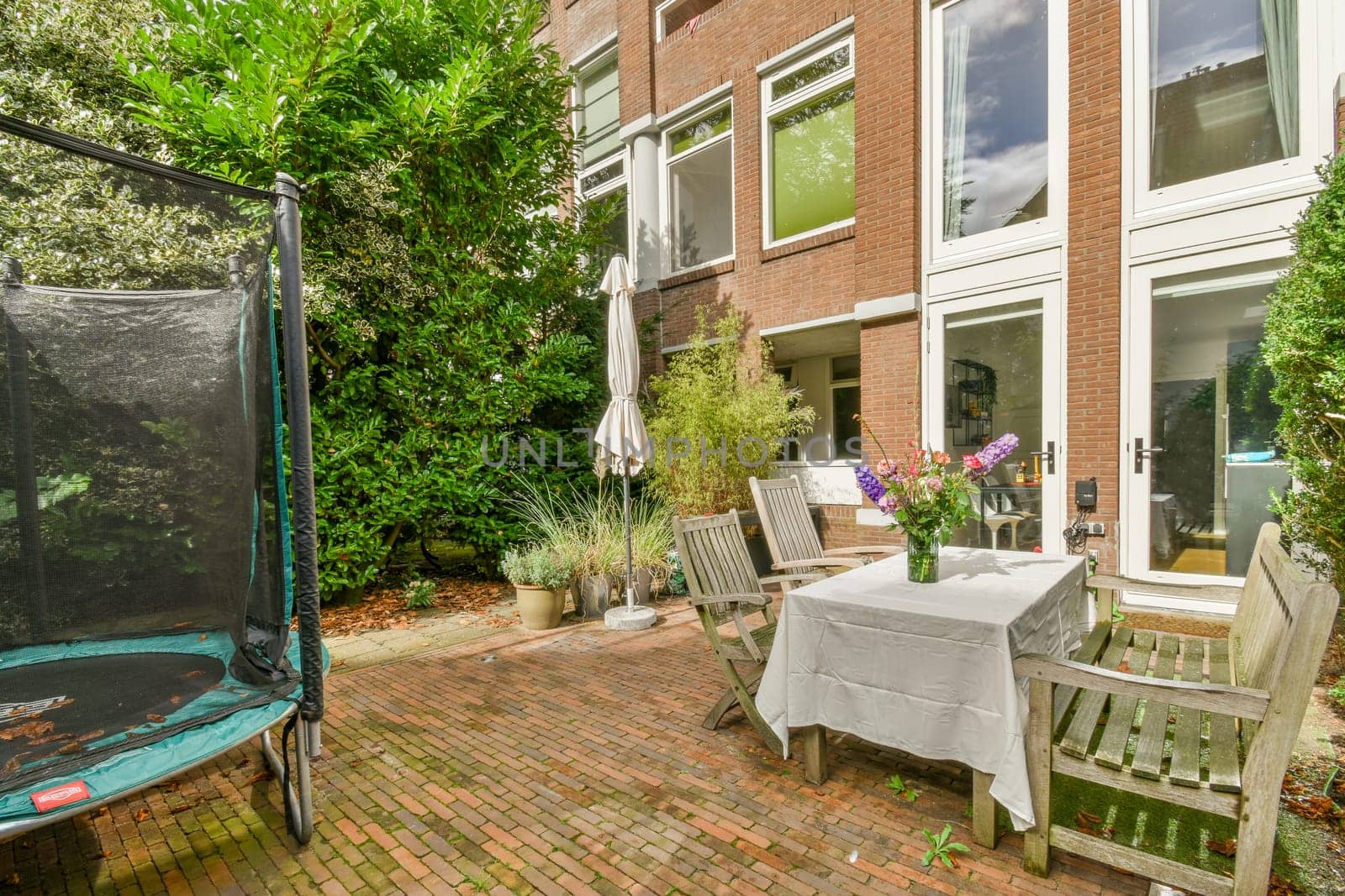 a patio with chairs, table and an umbrella on it's side door to the back of a house