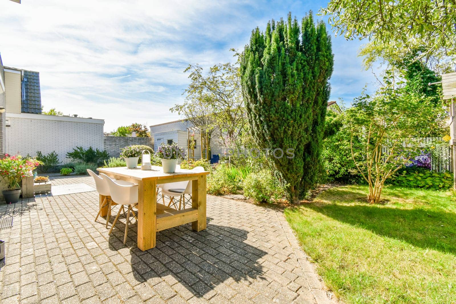 a backyard area with a table and chairs in the middle, surrounded by green trees on either side of the yard