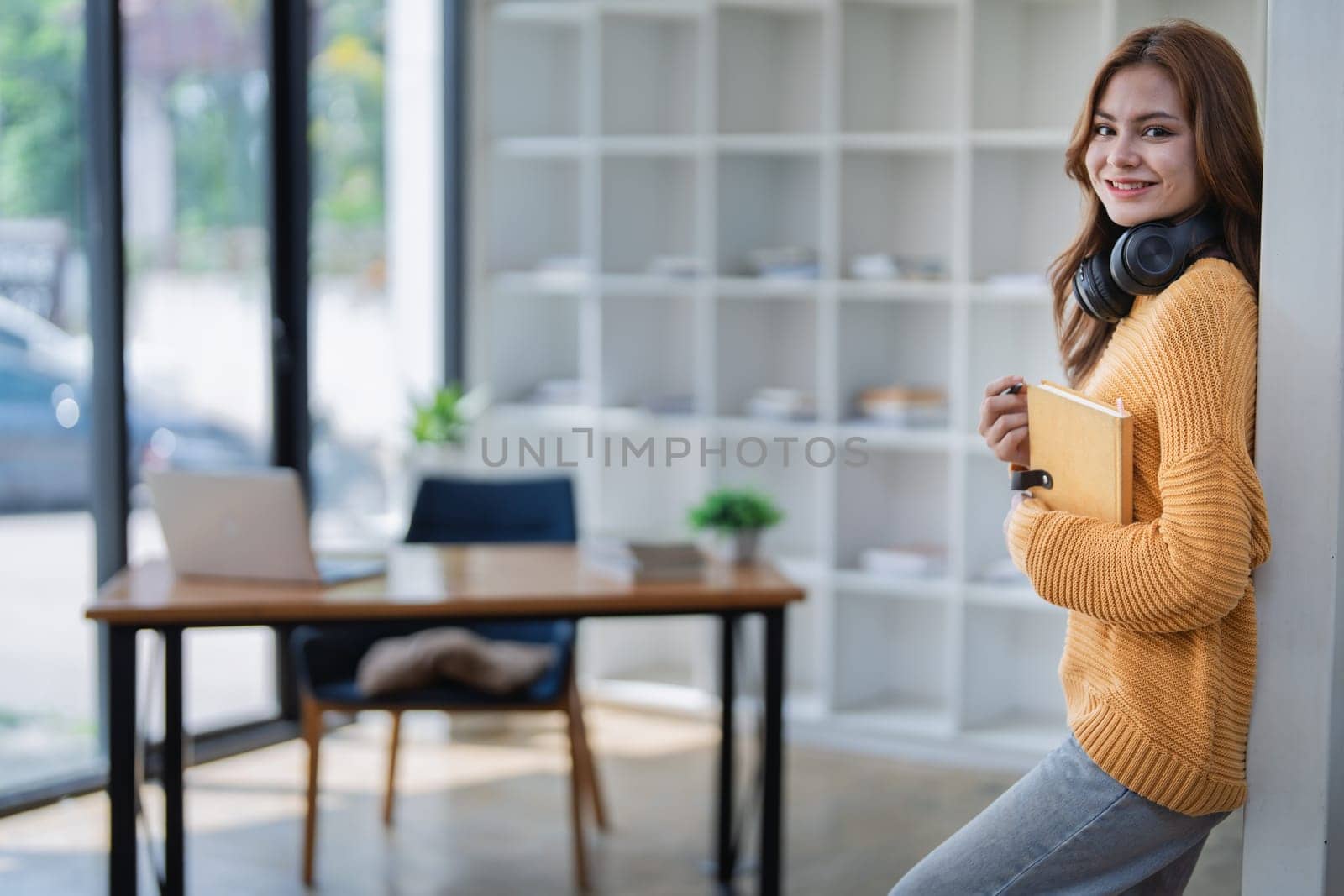 happy young woman with headphones is immersed in a book, happily learning.