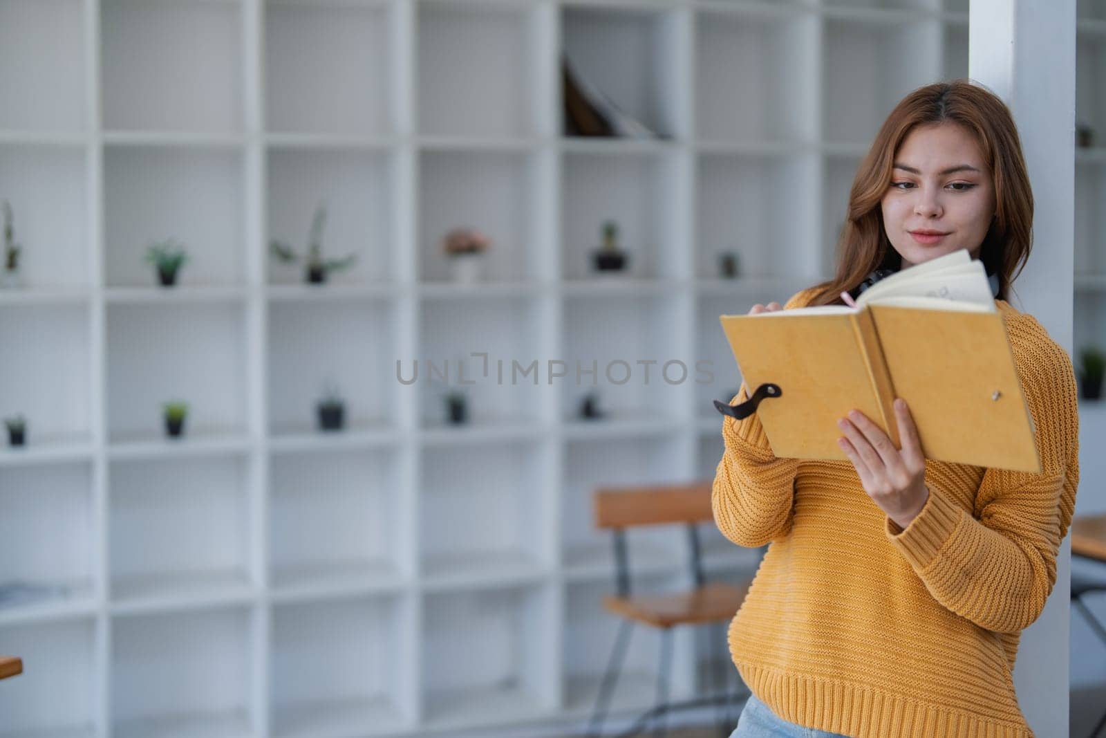 happy young woman with headphones is immersed in a book, happily learning.