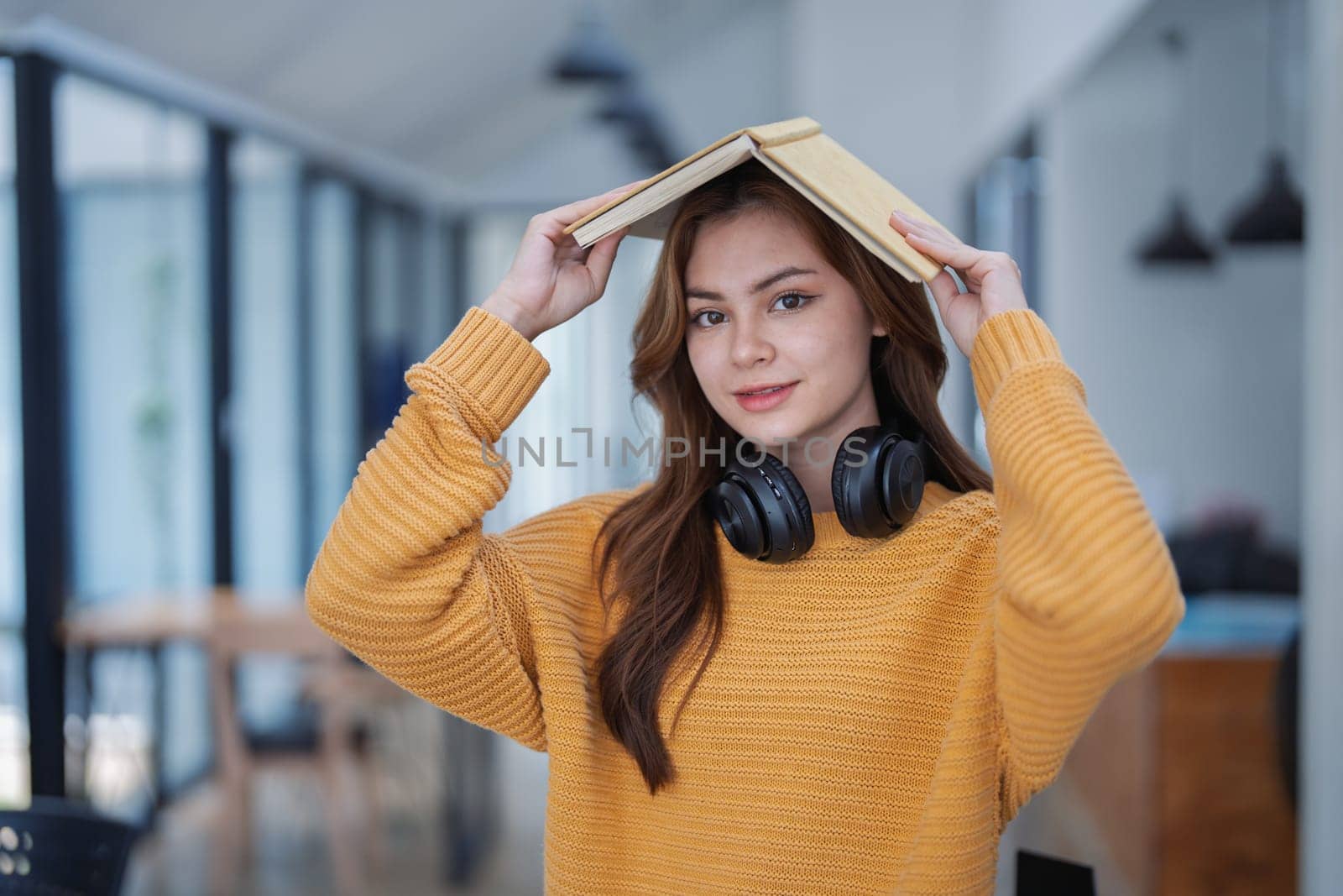 happy young woman with headphones is immersed in a book, happily learning.