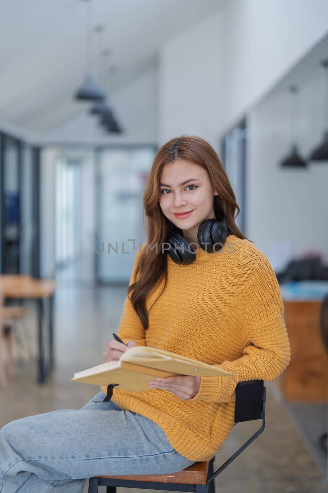 happy young woman with headphones is immersed in a book, happily learning.
