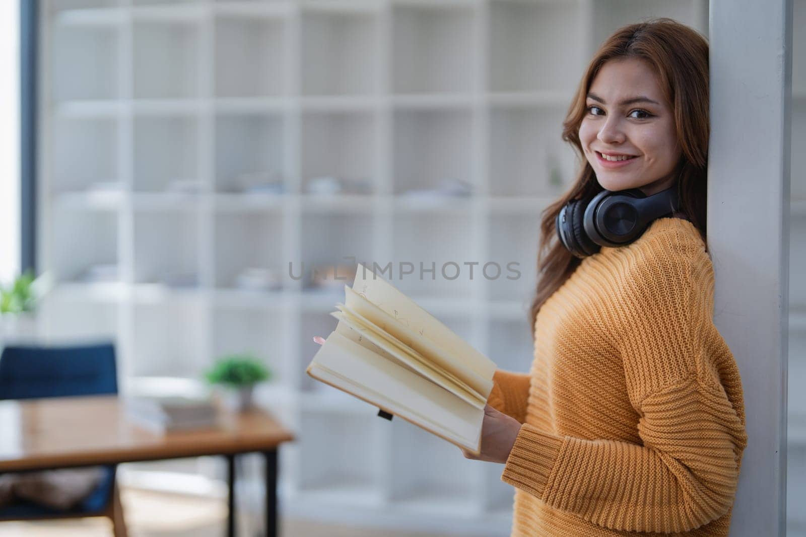 happy young woman with headphones is immersed in a book, happily learning.