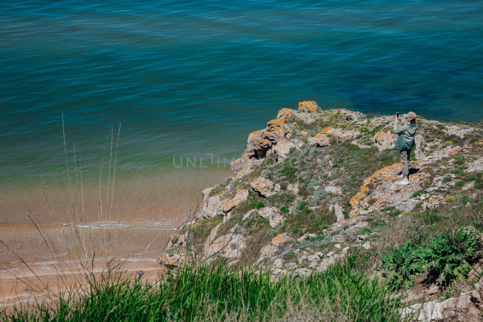 Female tourist taking photos of seascape from top of cliff