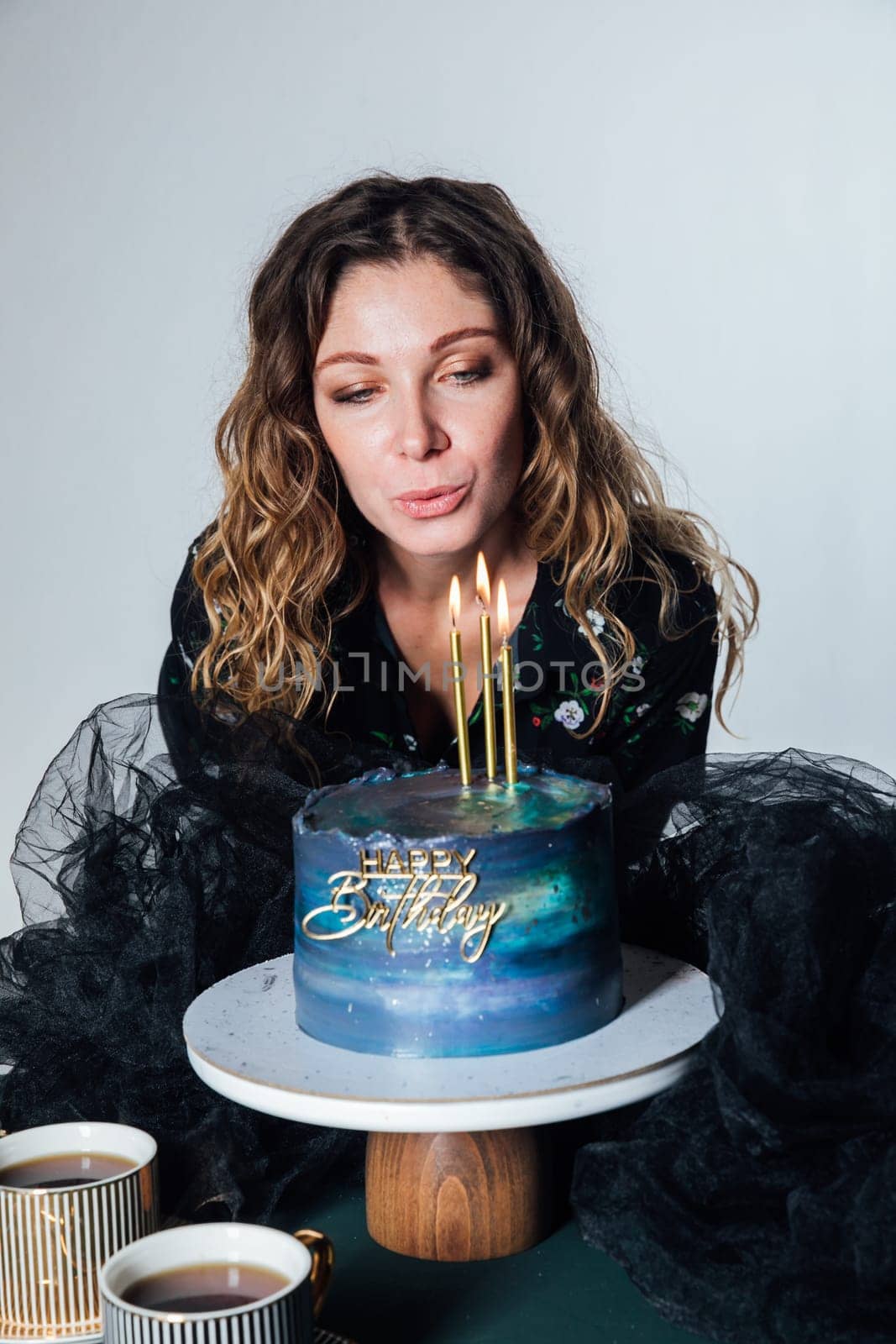 Beautiful woman blowing out candles on birthday cake