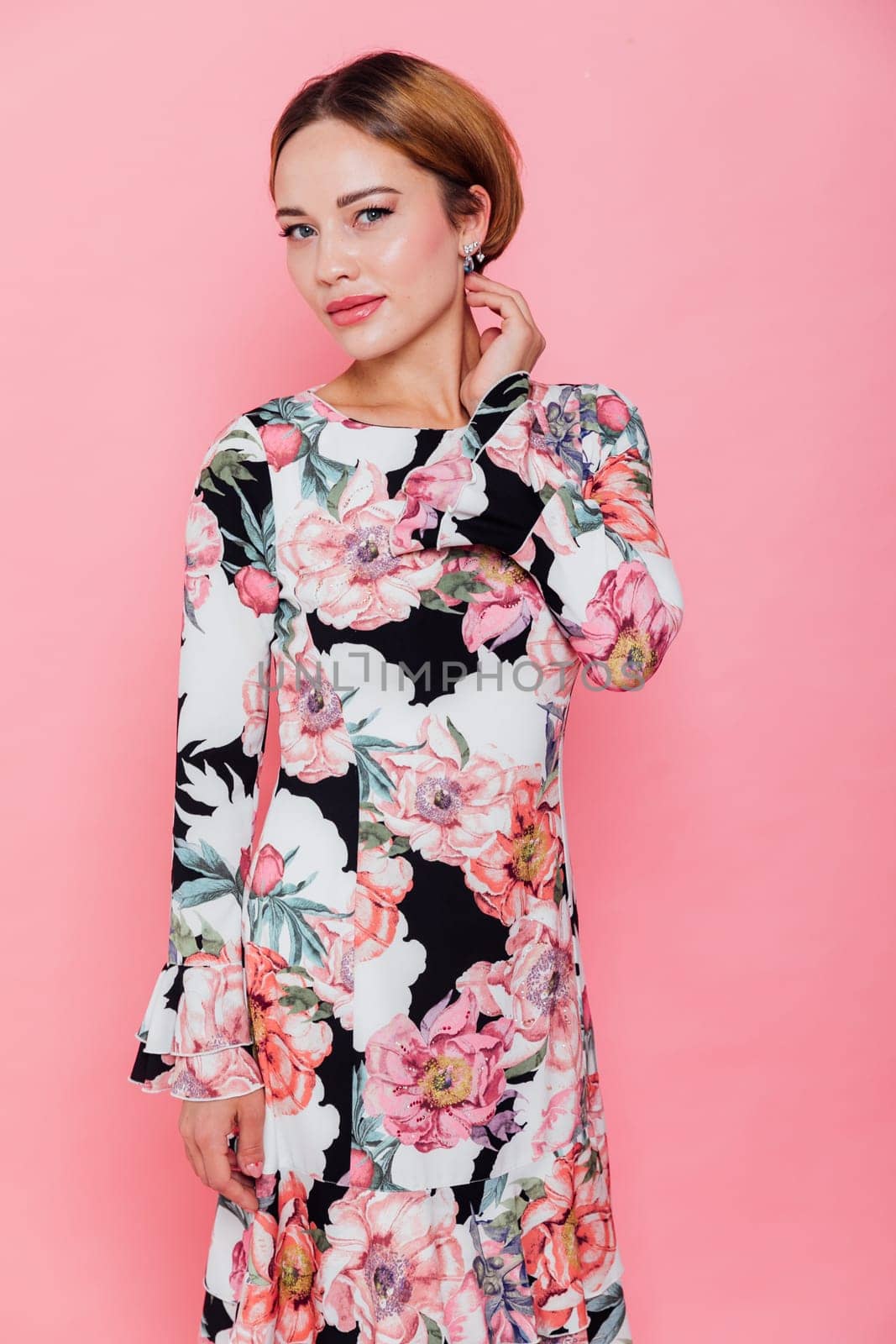 Beautiful fashion blonde woman in summer dress with flowers on pink background smiling