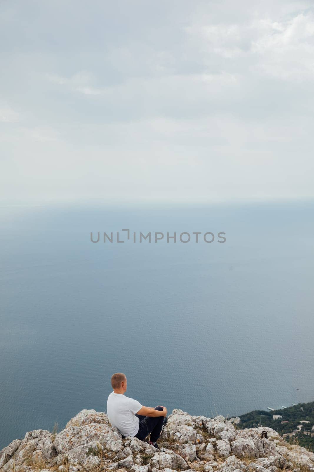 Man hiking looking landscape at sky with clouds and green forest from mountain top