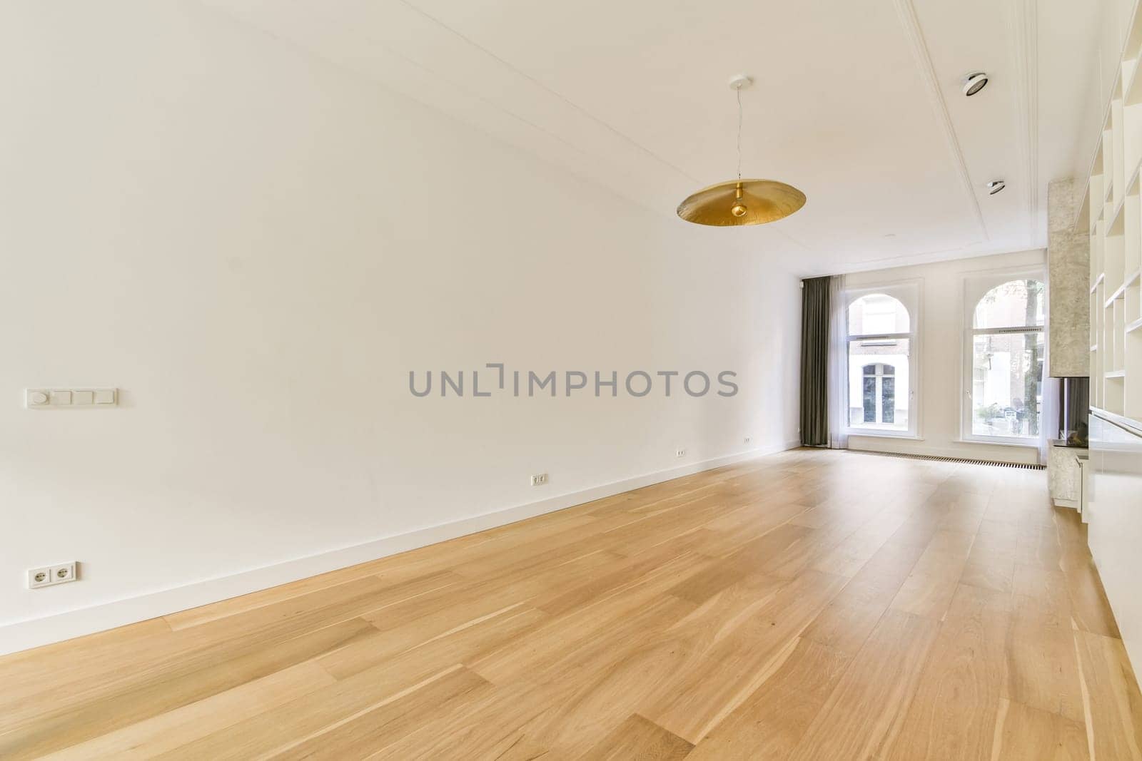 A bright and airy room featuring wooden flooring, high ceilings, and large windows that let in natural light, creating an inviting and open atmosphere.