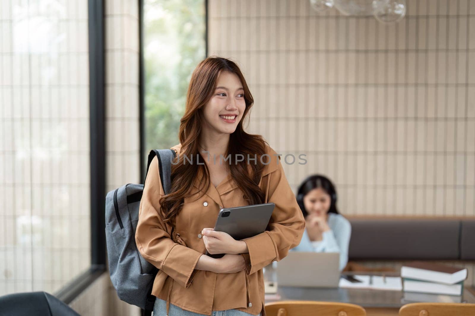 Carrying a tablet, a motivated student walks into a modern cafe, excited to engage in productive study sessions and networking.